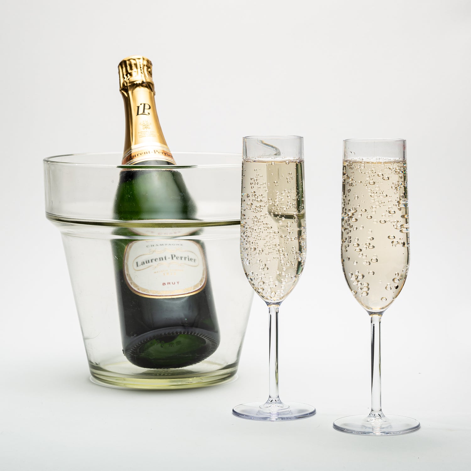 two unbreakable plastic champagne glasses next to a bottle of champagne on ice